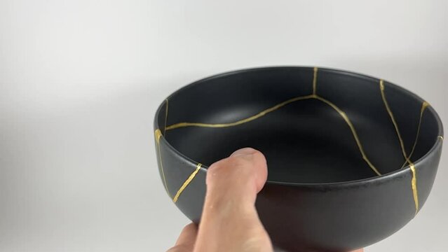 The making of kintsugi, artisan making kintsugi process. Slow motion cinematic video. Black Kintsukuroi bowl.
Closeup isolated.