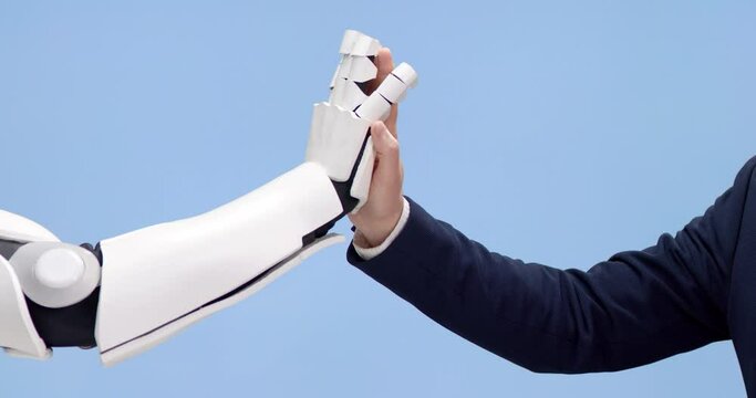 Modern white robot and successful businessman making high five gesture over blue studio background. Close up of hands. Unity of human and artificial intelligence.