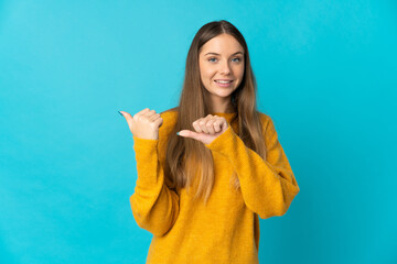 Young Lithuanian woman isolated on blue background pointing to the side to present a product