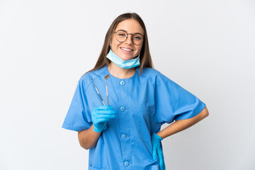 Lithuanian woman dentist holding tools over isolated background posing with arms at hip and smiling