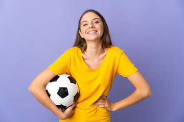 Young Lithuanian football player woman isolated on purple background posing with arms at hip and smiling