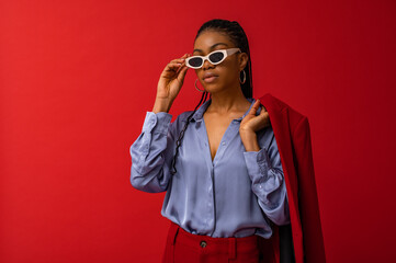 Fashionable Black woman wearing classic satin shirt, trendy sunglasses. Fashion studio portrait....
