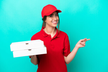 Pizza delivery woman with work uniform picking up pizza boxes isolated on blue background pointing...