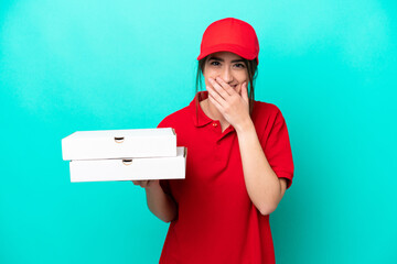 Pizza delivery woman with work uniform picking up pizza boxes isolated on blue background happy and smiling covering mouth with hand