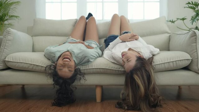 Roommate concept of 4k Resolution. Asian women lying upside down on the sofa talking.