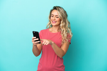 Fototapeta premium Young Brazilian woman isolated on blue background sending a message or email with the mobile