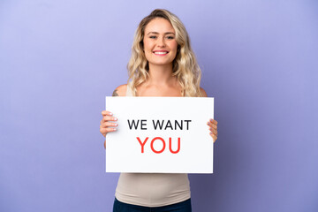 Young Brazilian woman isolated on purple background holding We Want You board with happy expression