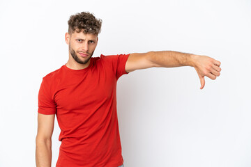 Young caucasian handsome man isolated on white background showing thumb down with negative...