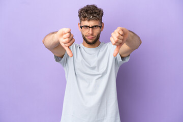 Delivery caucasian man isolated on purple background showing thumb down with two hands