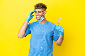 Dentist blonde man holding tools isolated on background smiling a lot