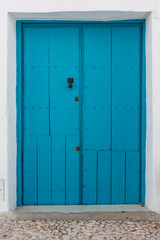 Rustic, blue door with black knocker in Frigiliana. Malaga, Andalusia, Spain