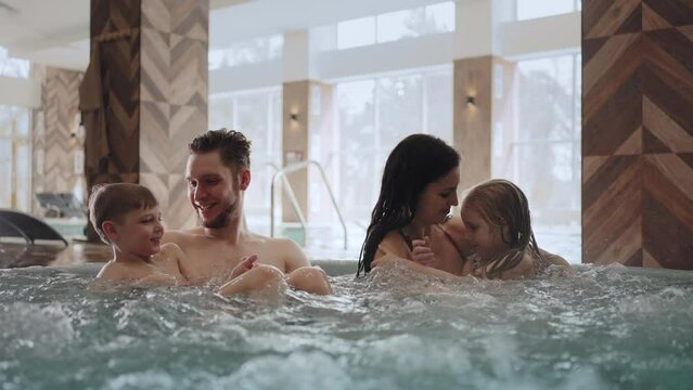 modern balneological center with thermal water, happy family with children is relaxing in jacuzzi bath