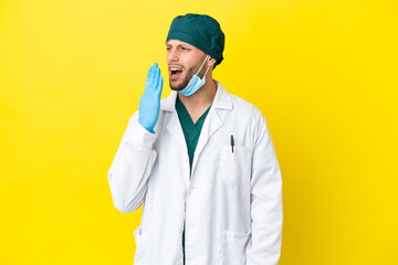 Surgeon blonde man in green uniform isolated on yellow background yawning and covering wide open...
