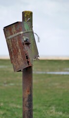 Rostige Box mit Löchern in der Küstenlandschaft