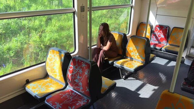 girl Riding the train there is no one She is alone she is in a brown suit beautiful with blond hair on the street, spring, trees flash by, slow motion video, she thinks. High quality 4k footage