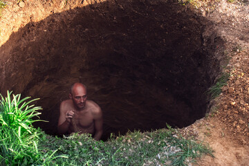 Man with naked torso digging a hole in the ground - obrazy, fototapety, plakaty