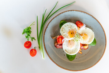 Scrambled eggs with bacon tomatoes and herbs on a white table