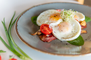 Scrambled eggs with bacon tomatoes and herbs on a white table