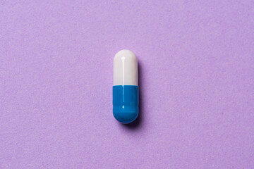 White and blue medicine pill on a table.