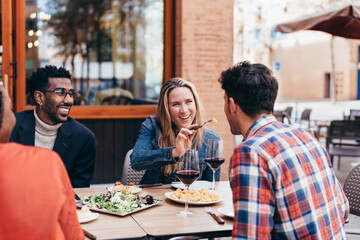 happy Caucasian woman offering a french fry to another diner