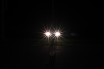 car headlights in a starburst shape form a backlight for a skateboard in the dark of the night