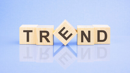 Trend - word is written on wooden cubes on a blue background. close-up of wooden elements