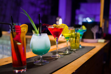 A row of different martini glasses on the counter in a bar