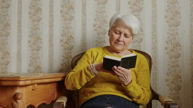 Mature Caucasian woman reading Bible, horizontal slowmotion. High quality 4k footage