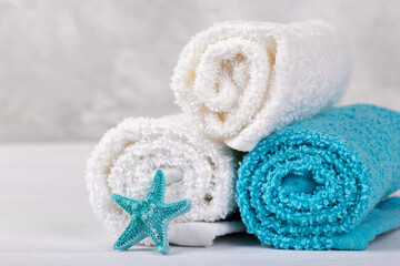 Spa composition with white and blue soft rolled cotton towels and star fish copy space