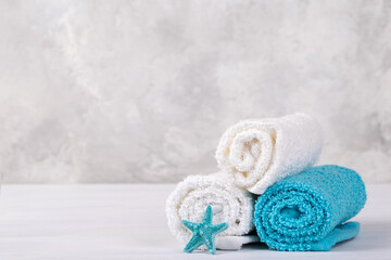 Spa composition with white and blue soft rolled cotton towels and star fish copy space