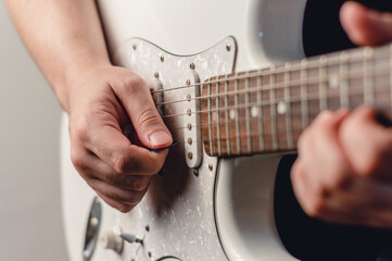 unrecognizable man playing electric guitar with plectrum