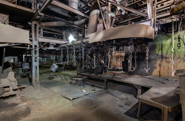 Interior of an old bankrupt automobile factory. Stopped overhead conveyor with hooks for fastening parts