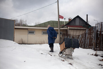 Retired Russian grandmother takes her things in a sleigh. Grandmother in winter is looking for where to survive. Hope only in their own strength.