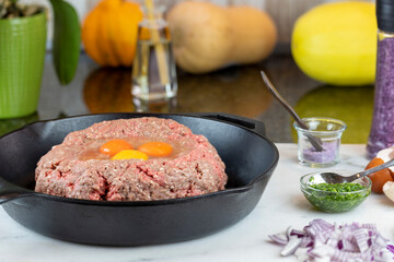 Preparation of a meatloaf with eggs, and spices, in a cast iron pan for roasting