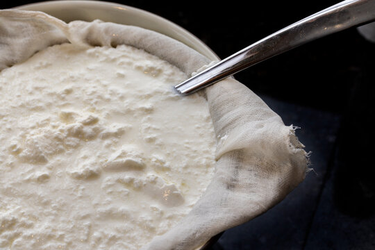 Homemade yogur being processed through cheesecloth to drain whey
