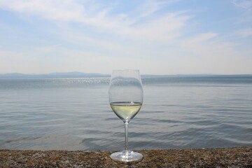 Weinglas mit Weißwein auf der Kaimauer am Bodensee