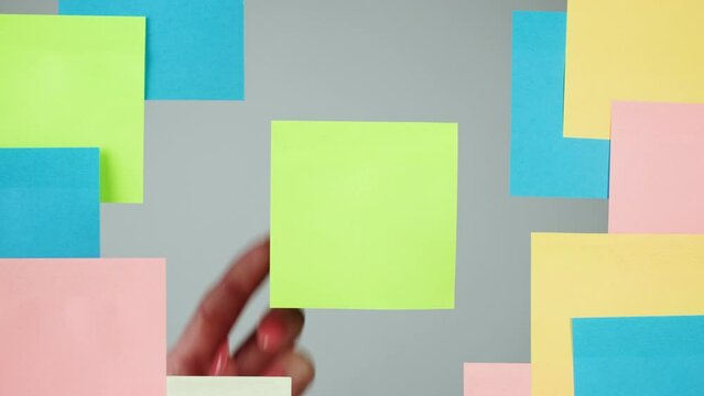 Note sticker on transparent glass close-up. Working in office, creative designer using colorful reminder papers.