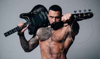 Guitarist breaks guitar. Excited sexy man with electric guitar. Macho with muscular torso with...