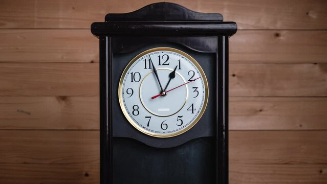 Timelapse of vintage clock with full turn of time hands at 1 am or pm on wooden background. Old Retro wall clock with white circular dial. Old-fashioned antique clock. Arrows second, minute, and hour