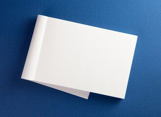 Blank memo pad with page folded back on blue surface.