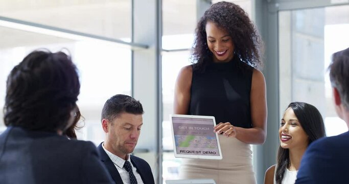 Running through new business models. 4k video footage of a businesswoman using a digital tablet while giving a presentation to her colleagues in an office.