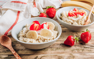 Quinoa porridge with coconut milk and fresh strawberries on wooden rustic background. Healthy Lactose and Gluten Free Breakfast.