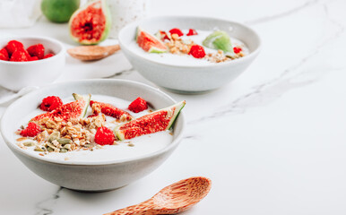 Granola with yogurt, figs and raspberries in bowls