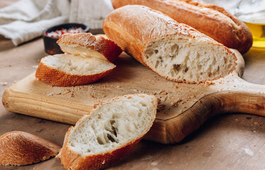 Homemade french two Baguette loafs and cut slice on wooden cutting board