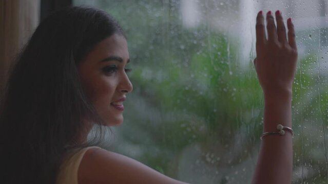 Close up shot of smiling face enjoying the rainy weather while seeing outside the window at Diu city of India.