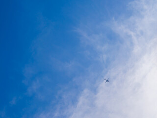 Beautiful blue sky with little silhouette airplane flying. Concept of transportation.