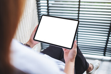 Mockup image of a woman holding digital tablet with blank white desktop screen in office