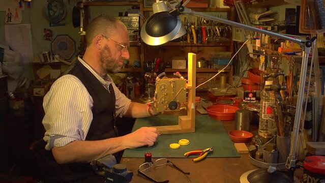 Clockmaker examining the mechanism of a clock on a jig