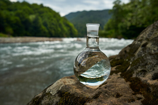 Bottle of drinking water on the shore of a mountain river.