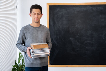 Portrait of arabic male teacher with books blackboard background. Back to school concept, education...